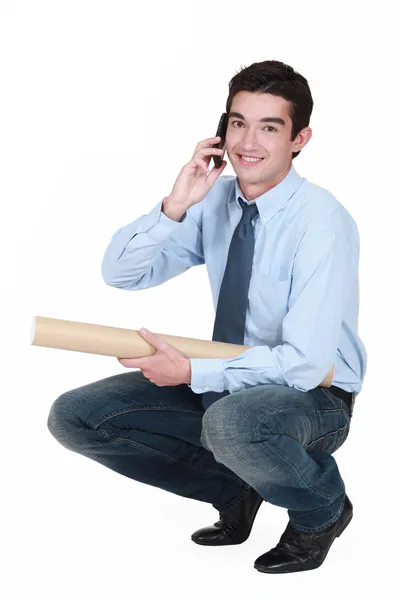 Squatting young professional talking on his mobile phone — Stock Photo, Image