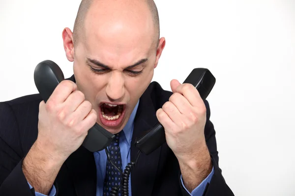 Bald man shouting into two telephones — Stock Photo, Image