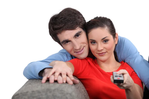 Couple sitting on a sofa with a remote control — Stock Photo, Image