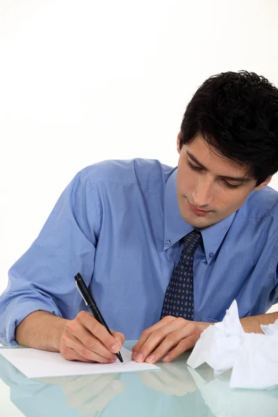 Frustrated man writing at desk Stock Photo