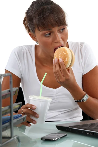 Hlad ženské výkonné jíst hamburger — Stock fotografie