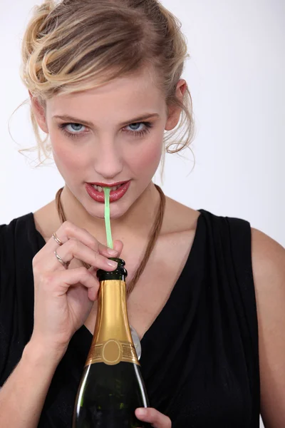 Vrouw die champagne drinkt door een rietje — Stockfoto