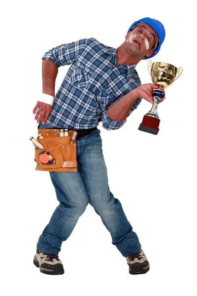 Accident prone construction worker holding a trophy — Stock Photo, Image