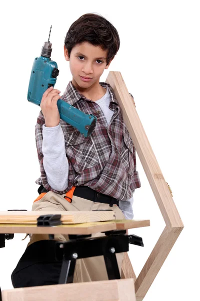 Ragazzino vestito come un artigiano che tiene un trapano — Foto Stock