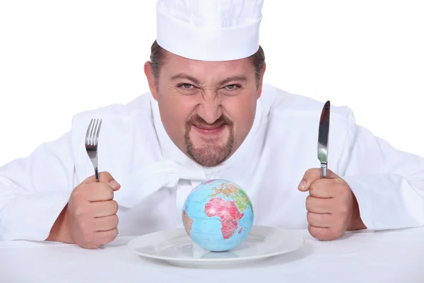 Šéfkuchař seděl s miniaturní zeměkoule na desce — Stock fotografie
