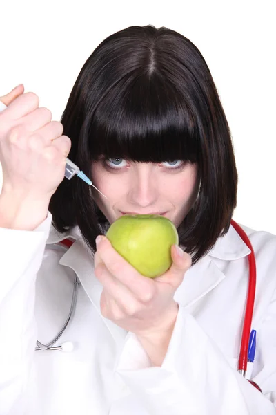 Жінка-лікар впорскує яблуко — стокове фото