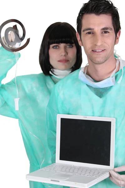Медицинские работники с ноутбуком и при вывеске — стоковое фото