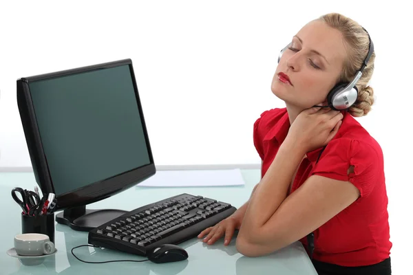 Blond office worker listening to music at desk — Stock Photo, Image