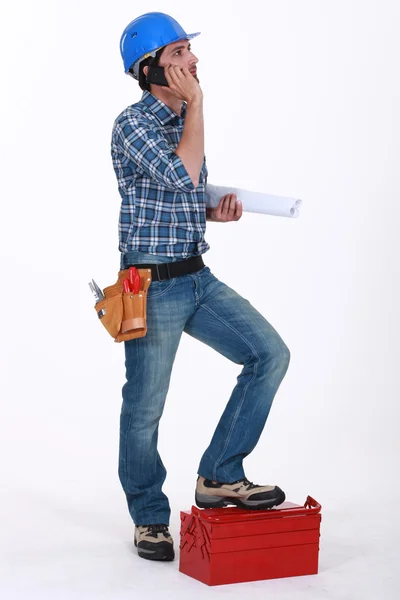 Builder with tool box making call — Stock Photo, Image