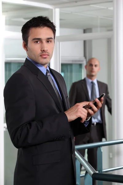 Businessman at the office holding a cell phone — Stock Photo, Image