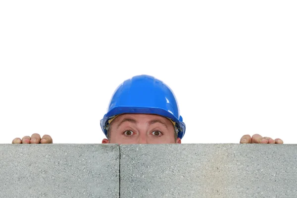 Trabalhador da construção escondido atrás de uma parede — Fotografia de Stock