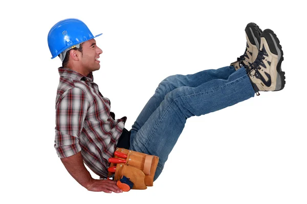 Craftsman sitting on the floor and raising his legs — Stock Photo, Image