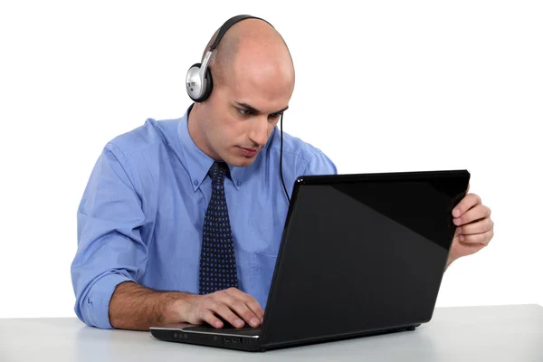 Empresario con auriculares y ordenador portátil —  Fotos de Stock