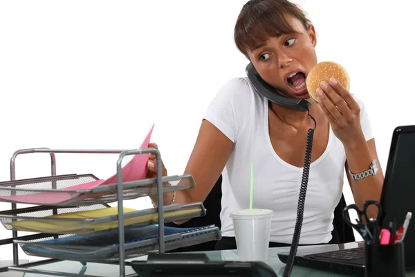 Femme occupée à manger à son bureau — Photo