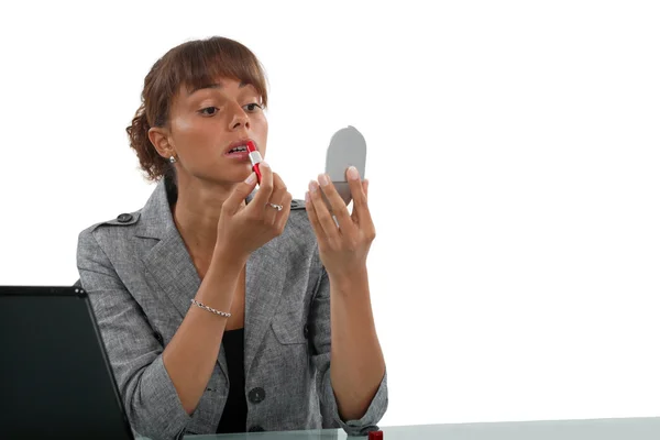 Geschäftsfrau trägt Lippenstift am Schreibtisch auf — Stockfoto