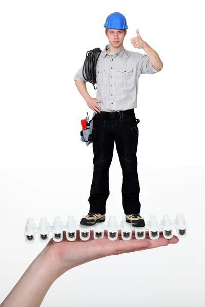 Handyman giving the thumbs-up whilst standing on giant hand — Stock Photo, Image