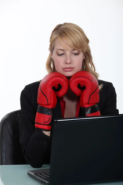 Businesswoman wearing boxing gloves and reading an e-mail — Stock Photo, Image