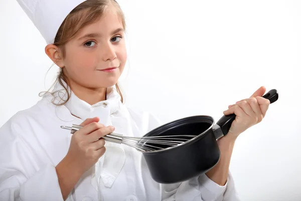 Ένα μικρό ξανθό κορίτσι, ντυμένοι με επικεφαλής μάγειρας είναι το μαγείρεμα — Φωτογραφία Αρχείου
