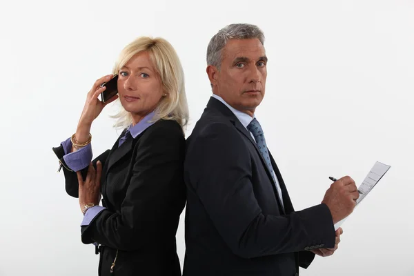Zakenman en zakenvrouw op de telefoon, rug aan rug — Stockfoto