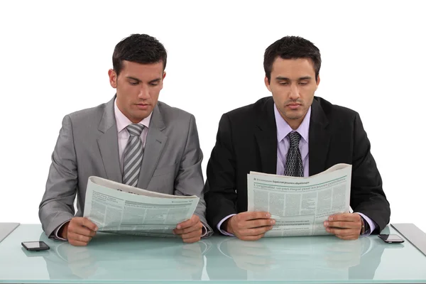 Two businessman sat with newspapers — Stockfoto