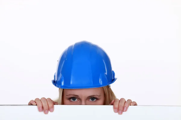 Handwerkerin blickt über eine niedrige Mauer — Stockfoto