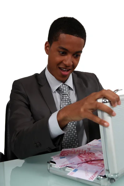 A con man opening a case full of money — Stock Photo, Image