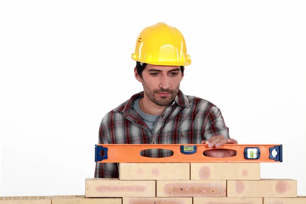 Mason comprobar el nivel de una pared de ladrillo — Foto de Stock