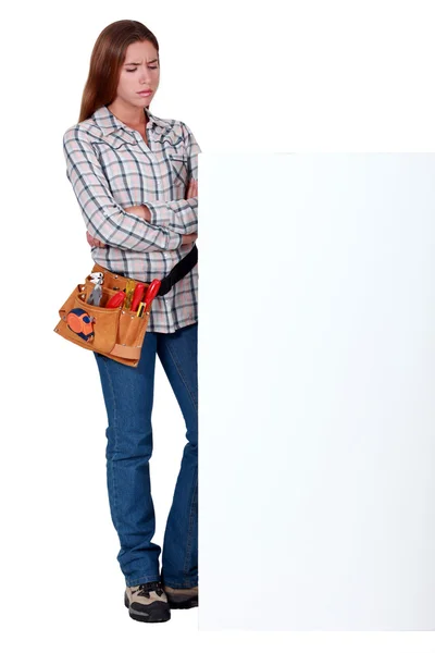 Craftswoman looking doubtfully at a blank ad board — Stock Photo, Image