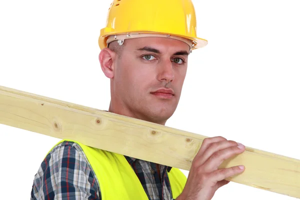 Labourer carrying a wooden plank Stock Image