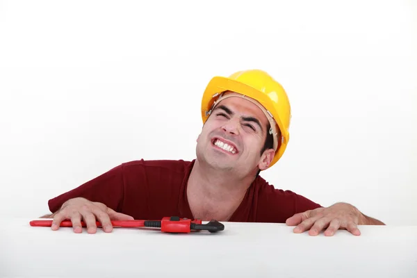 Grunting tradesman trying to lift himself up onto a ledge — Stock Photo, Image