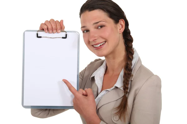 Young woman pointing to a blank clipboard — Stock Photo, Image