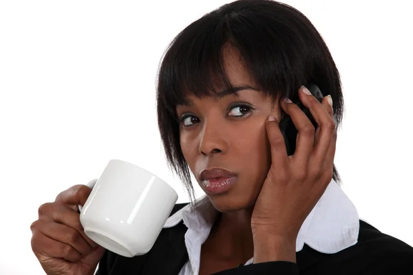 Mujer bebiendo una taza de té mientras habla por teléfono — Foto de Stock
