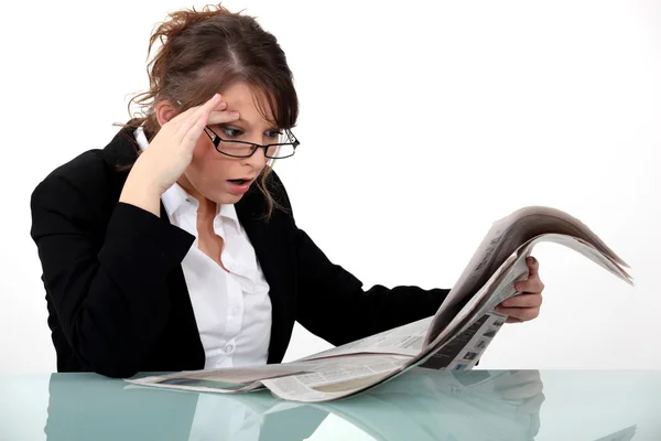 Vrouw staren naar de krant in ongeloof — Stockfoto