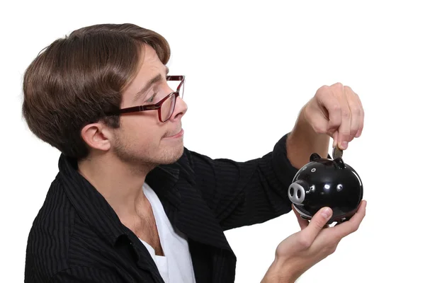 Man inserting a coin in a piggy bank — Stock Photo, Image