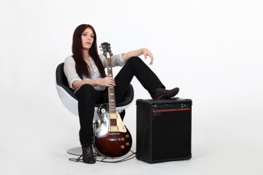 Woman with her foot propped on an amplifier and holding a guitar clipart