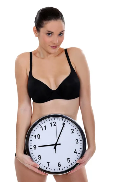 Kvinna i underkläder håller en klocka — Stockfoto