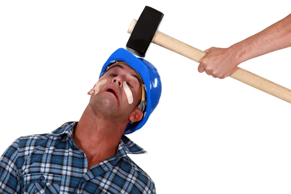 Injured tradesman being hit over the head with a mallet — Stock Photo, Image