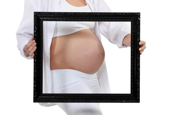 Pregnant woman holding a frame around her belly — Stock Photo, Image