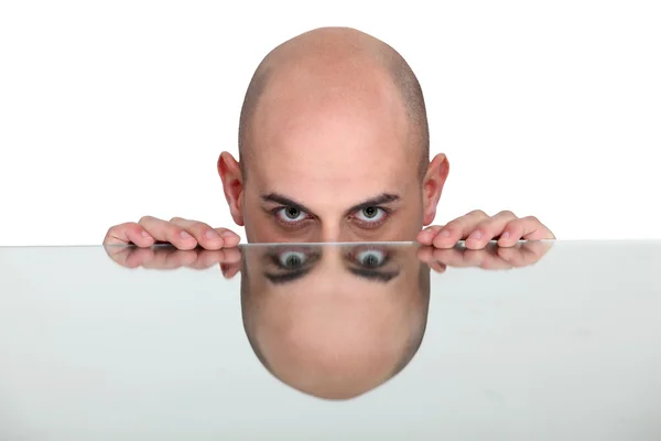 Bald man resting head on reflective surface — Stock Photo, Image