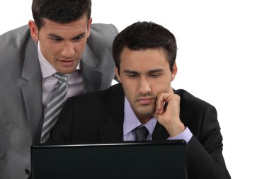 Businessmen looking at a laptop clipart