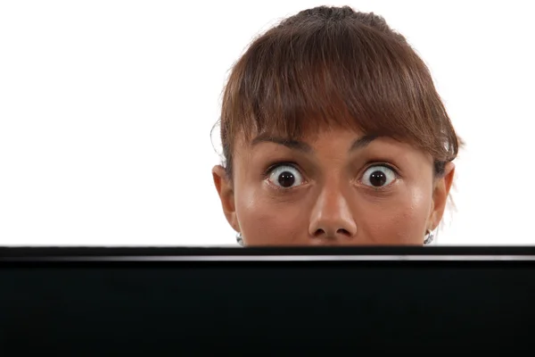 Wide-eyed woman peering over her laptop — Stock Photo, Image