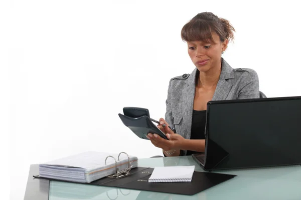 Femme d'affaires utilisant une calculatrice à son bureau — Photo