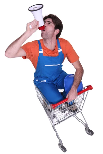 Builder with megaphone sat in shopping trolley — Stock Photo, Image