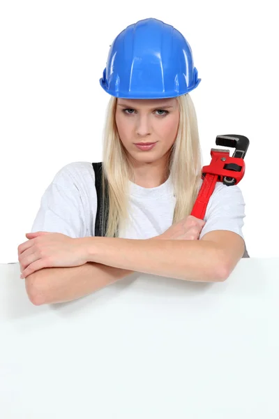 Woman with a wrench and board left blank for your message — Stock Photo, Image