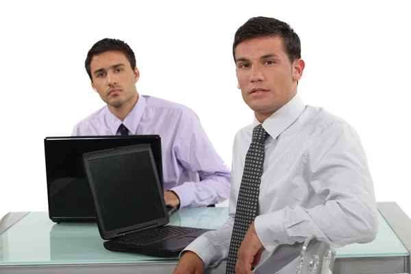 Two businessmen sat at the same desk Stock Image