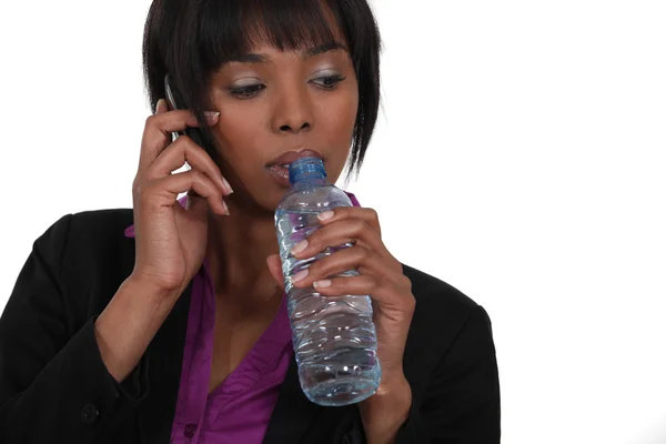 Woman with mobile phone drinking water — Stock Photo, Image