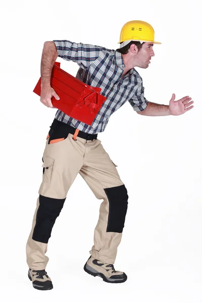 Builder stood in running position holding tool box Stock Image