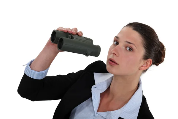 Curious businesswoman holding pair of binoculars — Stock Photo, Image