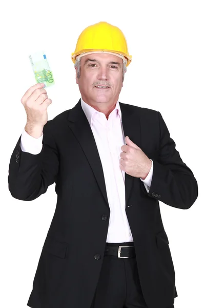 Empresario en un hardhat sosteniendo un billete de 100 euros — Foto de Stock