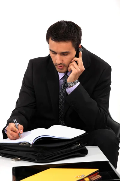 Businessman taking notes during important call — Stock Photo, Image